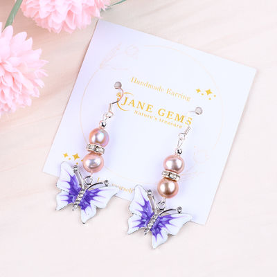 Boucles d'oreilles de perles d'eau douce violette de 9 mm avec charme papillon